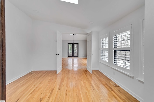 unfurnished room featuring french doors, visible vents, light wood-style flooring, and baseboards