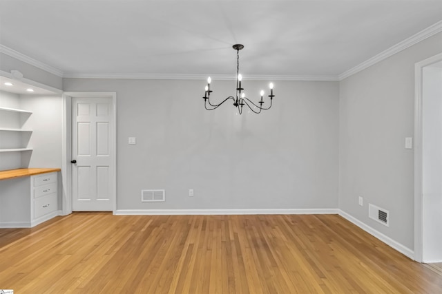 spare room featuring built in desk, light wood-type flooring, visible vents, and baseboards