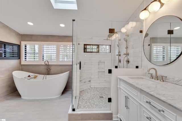 bathroom with a stall shower, a skylight, a soaking tub, vanity, and recessed lighting