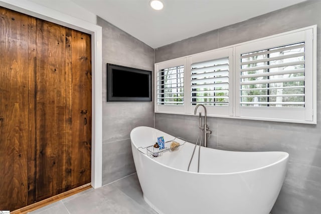 full bathroom with a soaking tub and tile walls