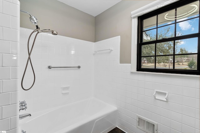 bathroom with shower / washtub combination, visible vents, and tile walls