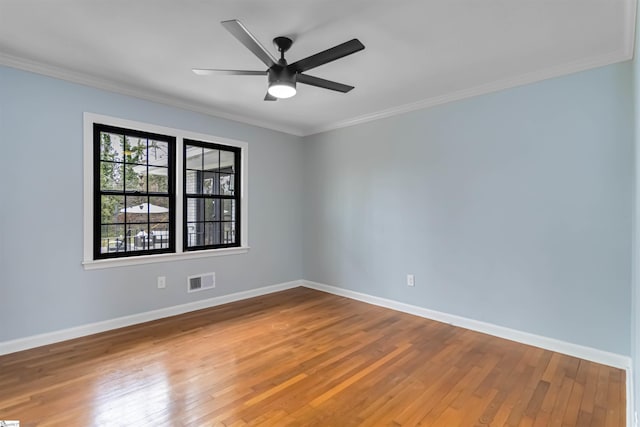 spare room featuring visible vents, a ceiling fan, baseboards, ornamental molding, and hardwood / wood-style floors