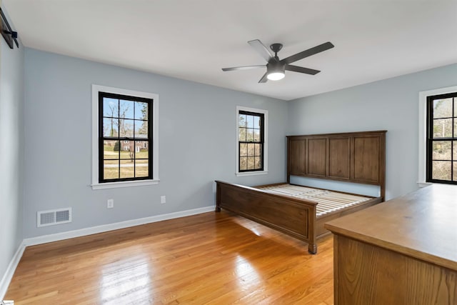 unfurnished bedroom featuring ceiling fan, light wood-style flooring, visible vents, and baseboards