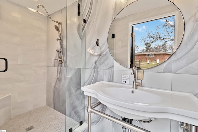 full bath with a sink, a shower stall, backsplash, and tile walls