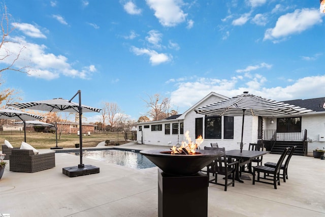 view of patio with an outdoor fire pit, a fenced in pool, and outdoor dining space