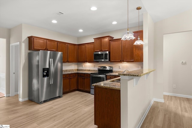 kitchen featuring a peninsula, light wood-style flooring, appliances with stainless steel finishes, and dark stone countertops