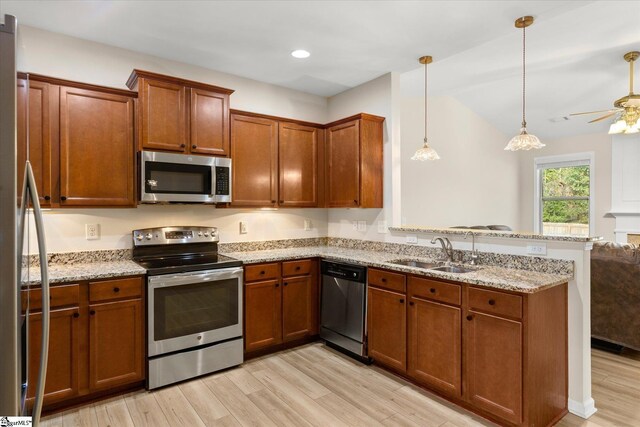 kitchen featuring a peninsula, brown cabinets, stainless steel appliances, and a sink