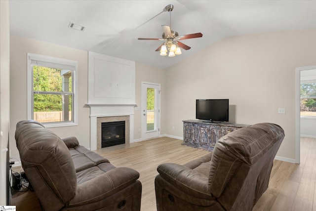 living area featuring a wealth of natural light, visible vents, vaulted ceiling, and light wood-style flooring