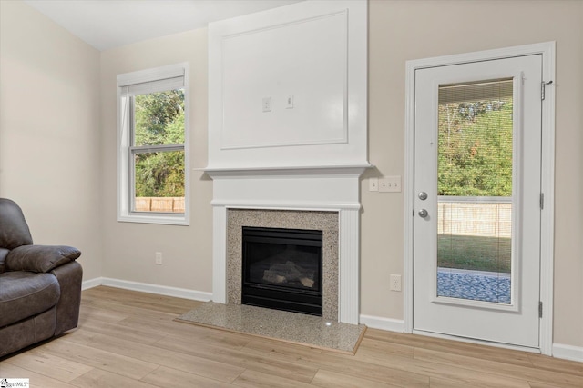 living room with a premium fireplace, baseboards, and wood finished floors