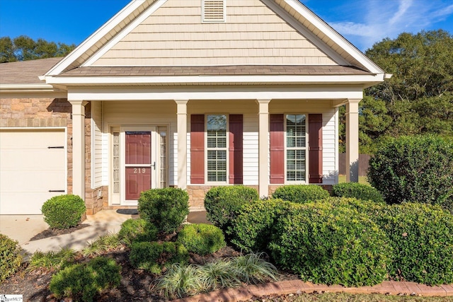 neoclassical home with an attached garage, stone siding, and a porch