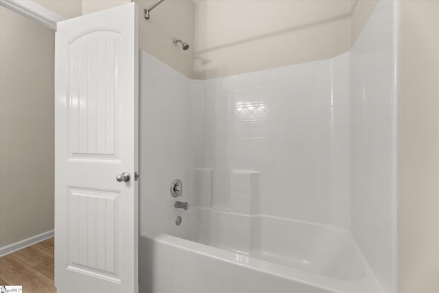 bathroom with bathtub / shower combination, wood finished floors, and baseboards