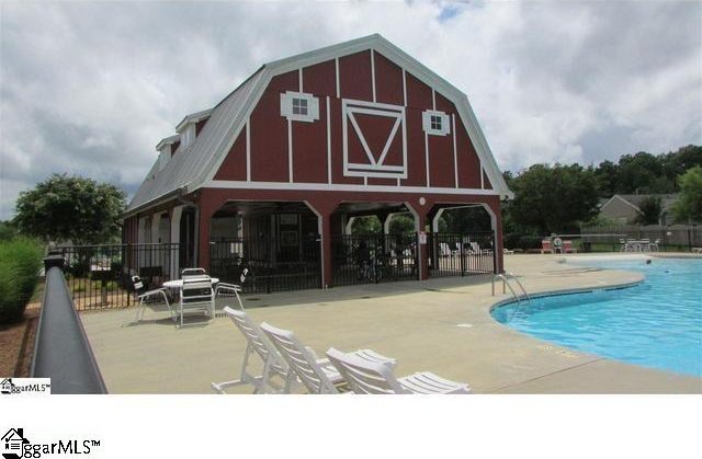 pool featuring a patio, a barn, and fence