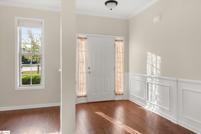 foyer entrance with a wainscoted wall, crown molding, a decorative wall, and dark wood-type flooring