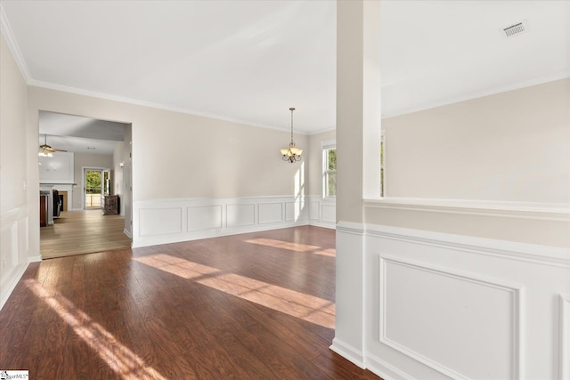 unfurnished room with visible vents, ceiling fan with notable chandelier, a fireplace, and hardwood / wood-style flooring