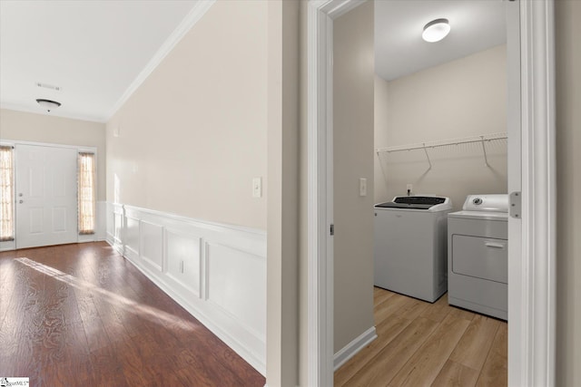 washroom with crown molding, light wood finished floors, a decorative wall, separate washer and dryer, and laundry area