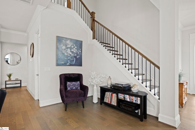 interior space with crown molding, a high ceiling, baseboards, and wood finished floors