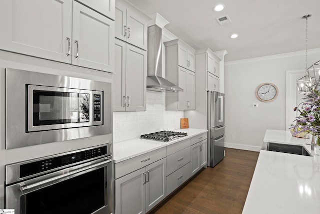 kitchen featuring visible vents, stainless steel appliances, decorative backsplash, light countertops, and wall chimney range hood