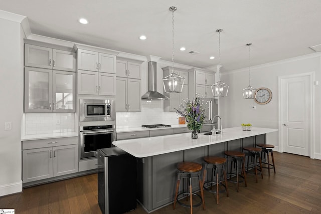 kitchen featuring dark wood-style floors, a sink, stainless steel appliances, a large island, and wall chimney range hood