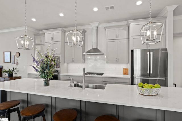 kitchen with wall chimney range hood, a notable chandelier, visible vents, and stainless steel appliances