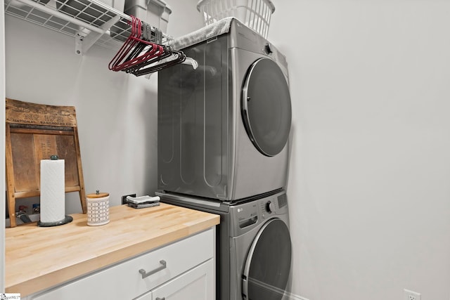 laundry room with cabinet space and stacked washer / drying machine