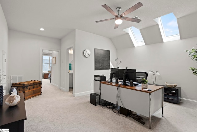 office area with light carpet, visible vents, lofted ceiling with skylight, and baseboards