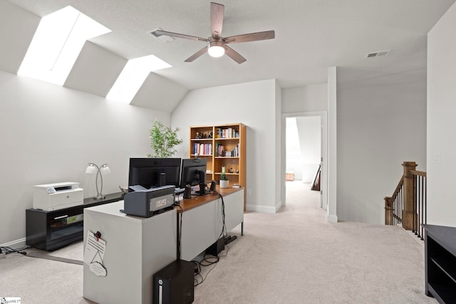 home office with visible vents, light carpet, ceiling fan, and lofted ceiling with skylight