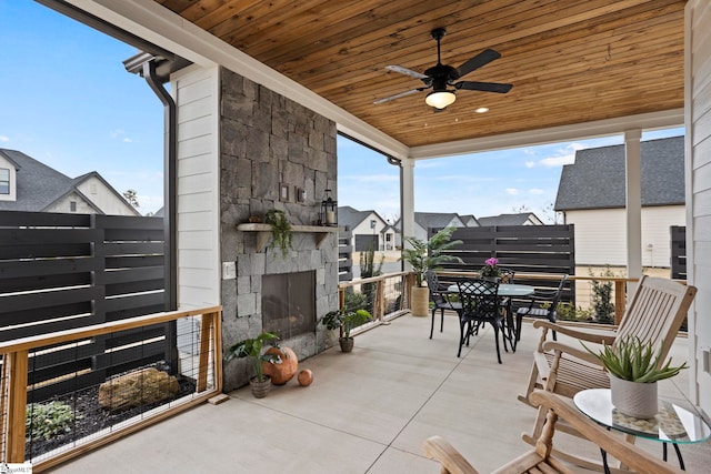 view of patio featuring outdoor dining area, an outdoor stone fireplace, and ceiling fan