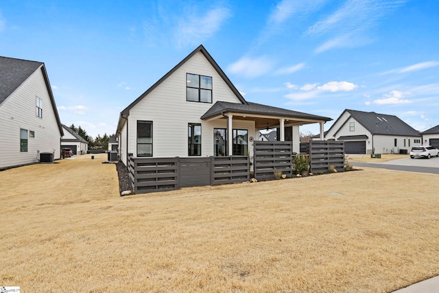 view of front facade with central AC unit, a front yard, and fence