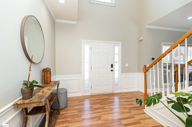 foyer with recessed lighting, ornamental molding, stairway, wainscoting, and light wood finished floors