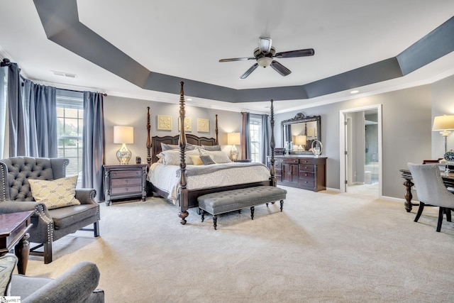 bedroom featuring connected bathroom, light colored carpet, visible vents, baseboards, and a tray ceiling