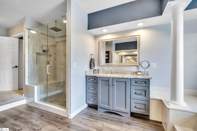 full bathroom featuring vanity, a stall shower, wood finished floors, and decorative columns