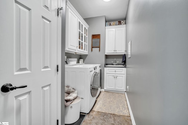 laundry room featuring cabinet space, a sink, baseboards, and separate washer and dryer