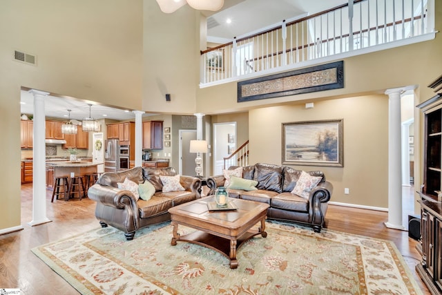 living room with ornate columns, visible vents, and light wood finished floors