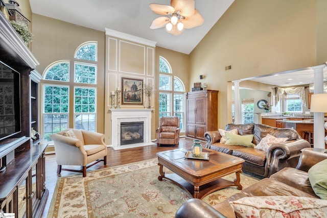 living room featuring a fireplace, decorative columns, visible vents, and wood finished floors