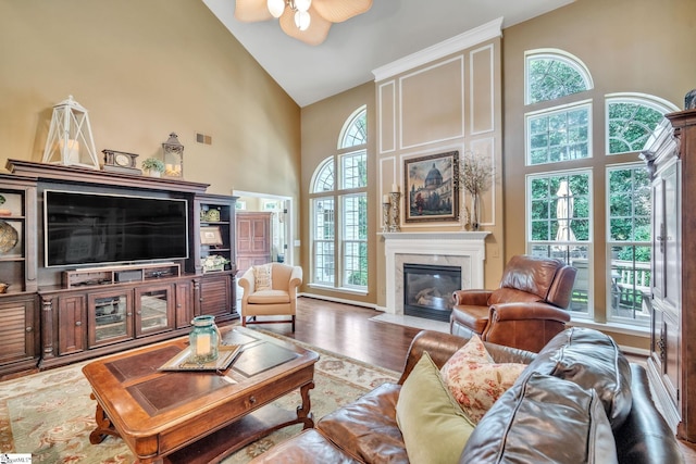 living room featuring high vaulted ceiling, plenty of natural light, wood finished floors, and a high end fireplace