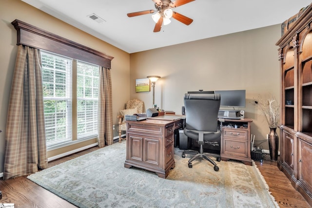 office space featuring wood finished floors, visible vents, and a ceiling fan