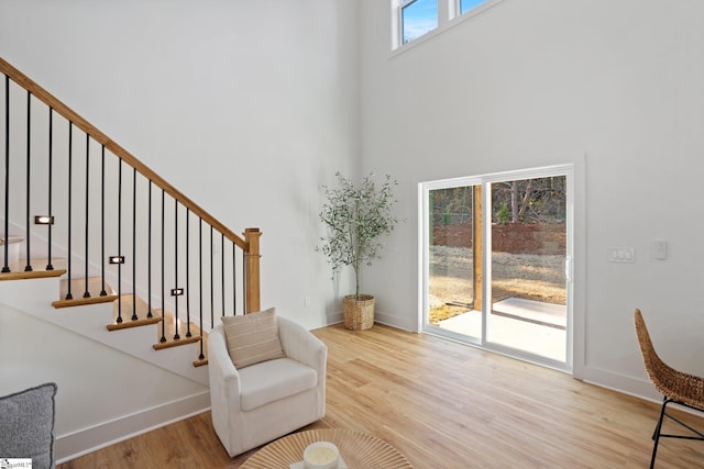 living area featuring baseboards, stairway, and wood finished floors