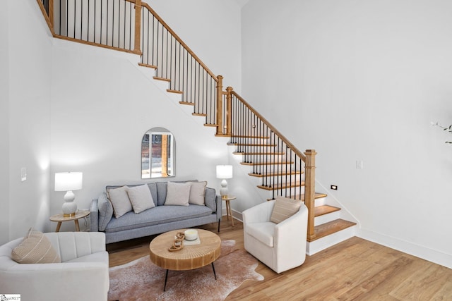 living room with light wood-style floors, baseboards, stairway, and a high ceiling