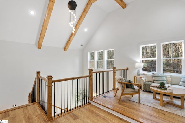 living area with high vaulted ceiling, beamed ceiling, wood finished floors, and an upstairs landing