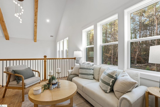 living area featuring visible vents, a chandelier, beamed ceiling, wood finished floors, and high vaulted ceiling