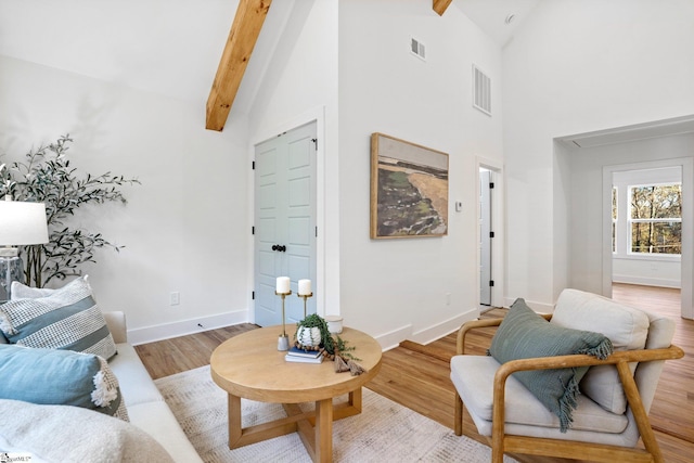 living room with visible vents, beamed ceiling, baseboards, and wood finished floors