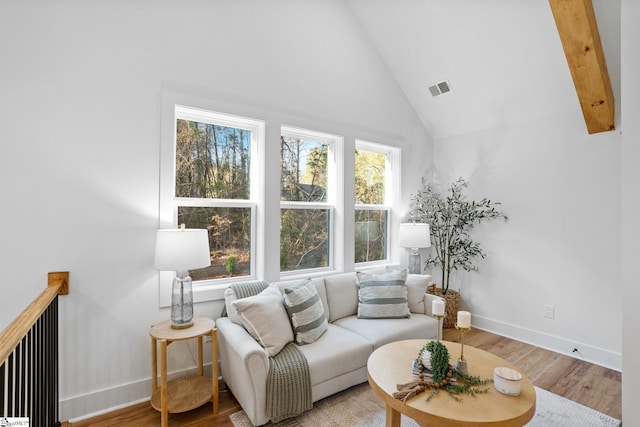 living room with high vaulted ceiling, light wood-style flooring, visible vents, and baseboards