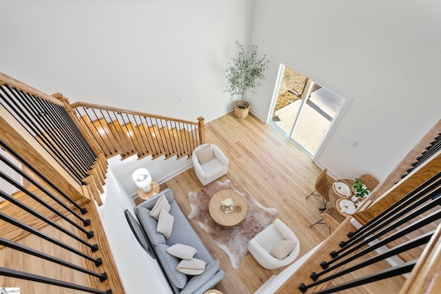 interior space with baseboards, stairway, a towering ceiling, and wood finished floors