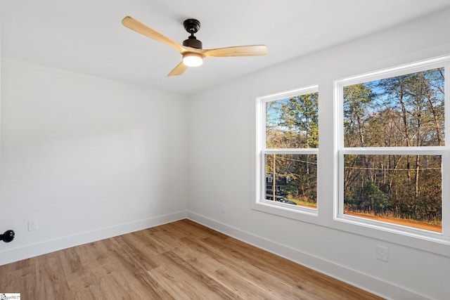 spare room featuring light wood finished floors, baseboards, and a ceiling fan