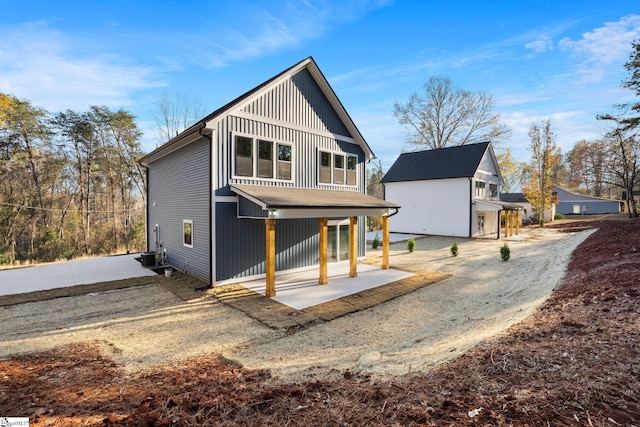 rear view of property with board and batten siding and a patio area