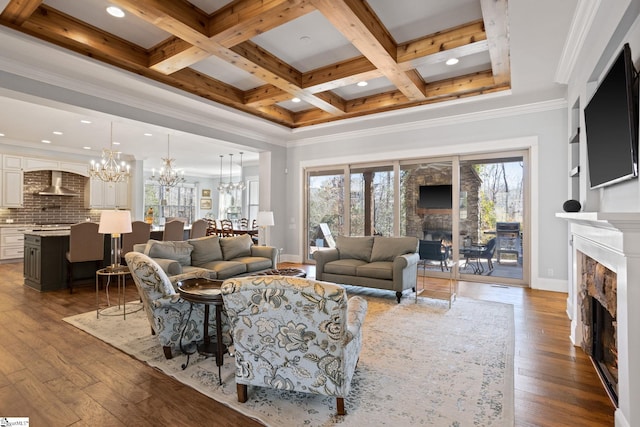 living area with coffered ceiling, dark wood-style floors, ornamental molding, a fireplace, and a notable chandelier