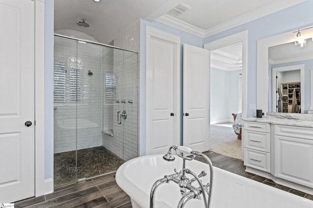 bathroom featuring a freestanding tub, wood finish floors, vanity, ornamental molding, and a shower stall