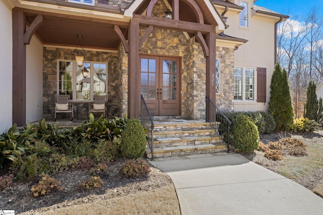 doorway to property with stone siding, covered porch, and french doors