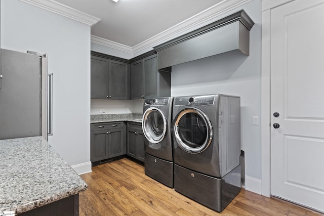 laundry area with light wood-style flooring, independent washer and dryer, cabinet space, and crown molding