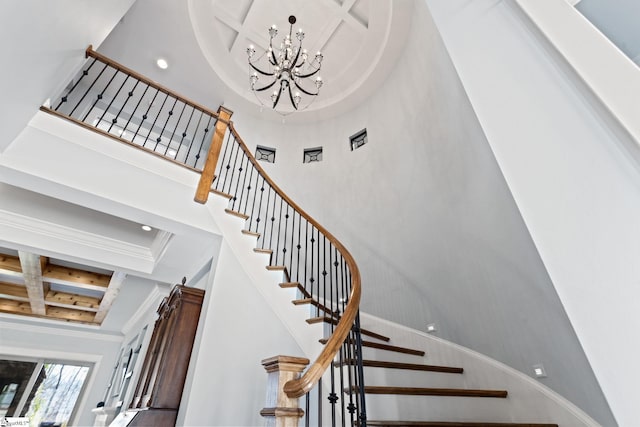 stairway with coffered ceiling, a towering ceiling, crown molding, a notable chandelier, and recessed lighting